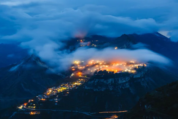 Gunib bir gece renkli ışıklar ile bulutlar dağ plato üzerinde Yayla Köyü. Popüler turistik yer. Güzel manzara ile uzun pozlama. Kafkas Dağları, Dağıstan Cumhuriyeti, Rusya Federasyonu