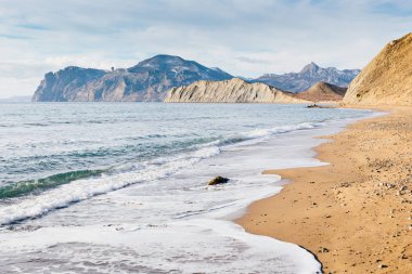 Sessiz Bay. Oda eğri kumlu plaj, dalgalar, cape bukalemun, Kara-Dag dağlar ve tepeler Güney kış gün güneşli manzara sahil kıyı. Karadeniz, Koktebel, Crimea