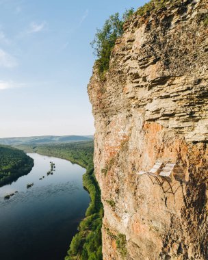 Krasnovishersk yakınlarındaki Vishera Nehri manzaralı Vetlan kaya duvarında dinlenme koltukları için alışılmadık bir yer, Perm krai, Rusya. Ural Dağları'nda popüler turistik yer