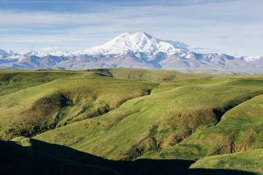Elbrus Dağı ve güneşli yaz sabahında yeşil dağlık çayırlar. Karachay-Cherkessia, Kuzey Kafkasya, Rusya 'daki dağ manzarası