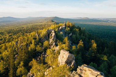 Gün batımında yeşil ormanın arasında kayalık Ural-Tau sırtı taşları, panoramik hava manzarası. Ural Dağları Zlatoust, Chelyabinsk Oblastı, Rusya yakınlarındaki vahşi doğa manzarası