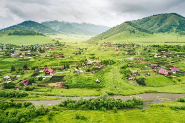 Nehirli yeşil dağ vadisindeki Cherga köyünün havadan görünüşü. Altai Cumhuriyeti, Sibirya, Rusya 'da kırsal yaz manzarası
