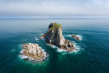 Güneşli bir yaz gününde mavi denizdeki kayalık adanın havadan görünüşü. Gamow Yarımadası yakınlarındaki Maximov Adası. Primorsky Krai, Uzak Doğu, Rusya 'da deniz manzarası