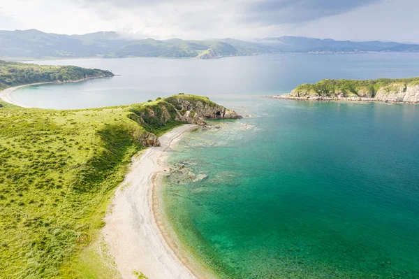 Turkuaz deniz suyuyla güzel körfezdeki kumsal. Gamov Yarımadası 'ndaki Cape Vkhodnoy' un güneşli yaz havası manzarası. Primorsky Krai, Uzak Doğu, Rusya 'da deniz manzarası