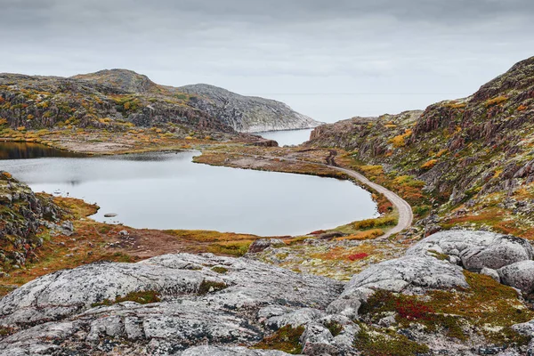 Teriberka yakınlarındaki Barents Denizi kıyısındaki göl etrafındaki kayalar ve taşlar. Sonbahar mevsiminde kuzey tundranın doğal manzarası. Kola Yarımadası, Murmansk Oblastı, Rusya