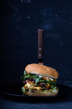 siyah plaka üzerinde bıçak ile klasik burger