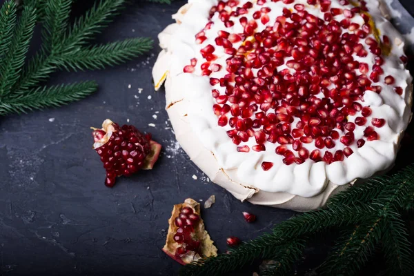 close-up of pavlova dessert with pomegranate seeds and christmas tree branches