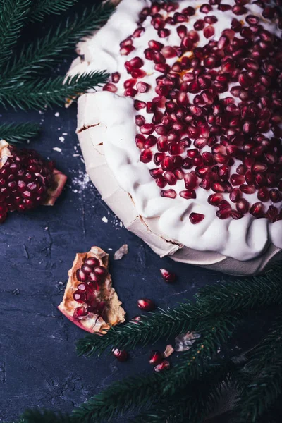 close-up of pavlova dessert with pomegranate seeds and christmas tree branches