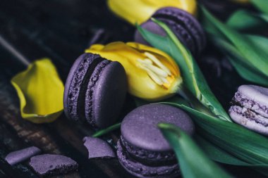 menekşe macarons sarı laleler koyu arka planda, seçici odak ile