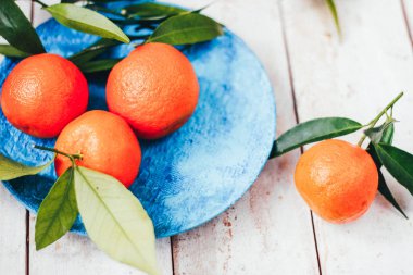 Mavi plaka, seçici odak üzerinde yeşil yaprakları ile taze mandalina