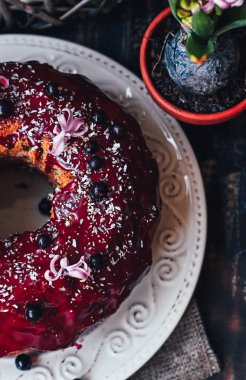ahşap arka planda beyaz plaka üzerinde siyah frenk üzümü kek, seçici odak