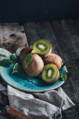 ahşap zemin üzerine mavi plaka üzerinde yeşil yaprakları ile kivi 