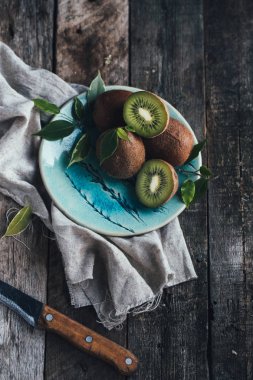 ahşap zemin üzerine mavi plaka üzerinde yeşil yaprakları ile kivi 