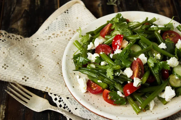 salad of green beans with tomatoes, cucumbers, cheese and greens