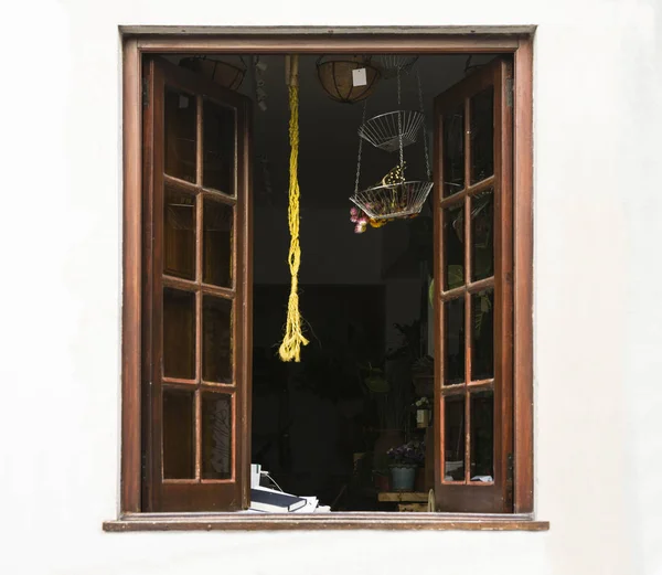 Open window on white background. Above the window-pots with a dry bouquet of flowers. Through the window you can see the interior of the room: flowers, books, furniture. Copy space.