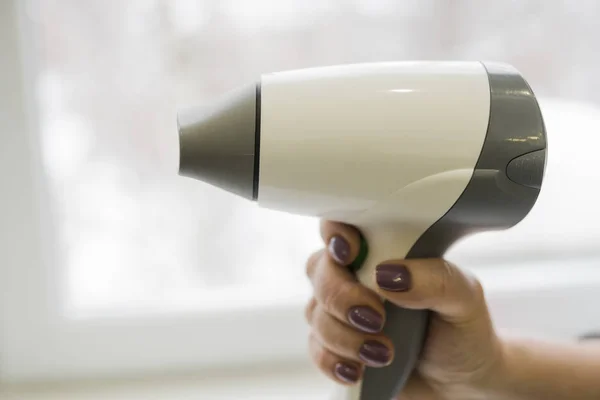 Woman\'s hand holding a hair dryer.  Selective focus. Copy space.