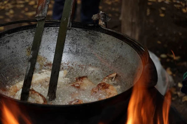 Food on a fire in the forest. Fish pieces are cooked in a pot. Selective focus.