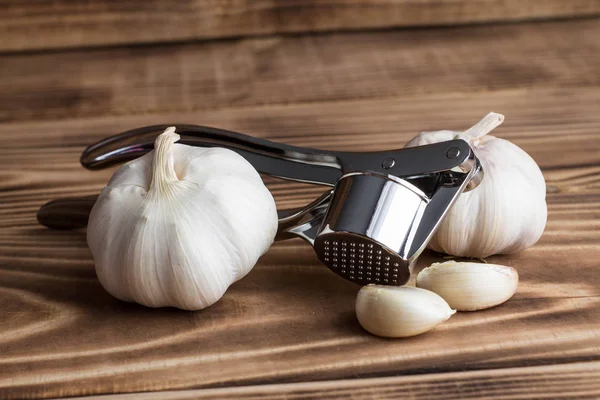 garlic and garlic press on a wooden table