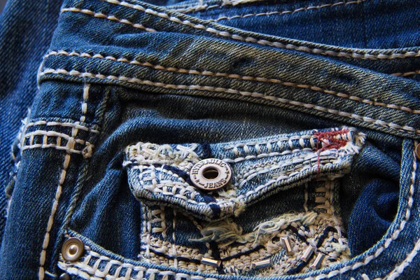 Close up of retro look denim jeans small front pocket with hand embellished embroidery stitching detail.