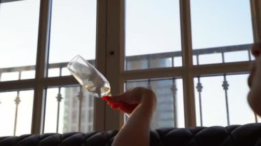 Bir bardak şampanya büyük bir pencere arka plan üzerinde yardım çerçevesinde, sonra çerçevede bir kadın kısa siyah saçlı ve dolgun dudaklar ile alır. Düşünceli pencereden dışarı bakıyor