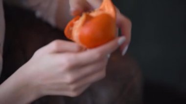 Kadın veya kız beyaz gömlek giymiş mandalina ya da portakal temizler, bir saati el üzerine beyaz çerçeve tek el ve meyve büyük planom6 çekim çivi