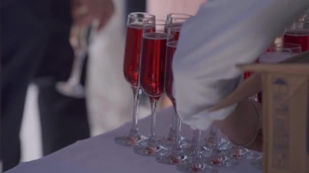 白いテーブル クロスとテーブルの上に ピンクのドリンク ワイン ワイングラス シャンパン 白シャツで手テーブルの上のグラスを置く 黒のジャケットの手はテーブルからガラス — ストック動画