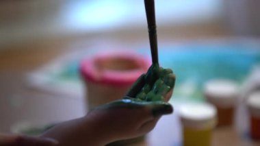 Anne boyayan çocuğun el ile yeşil boya / guaş, yakın çekim