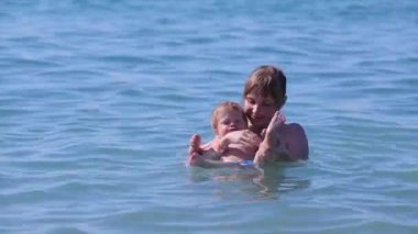 Anne/kadın / kız meşgul olan küçük bir çocuk / bebek / çocuk su / deniz / ona sırt üstü yüzmeyi öğretiyor