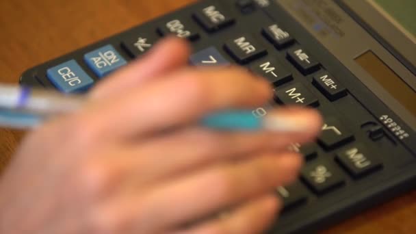女人的手 在他的手与圆珠笔获得数字 做计算器上的计算 — 图库视频影像