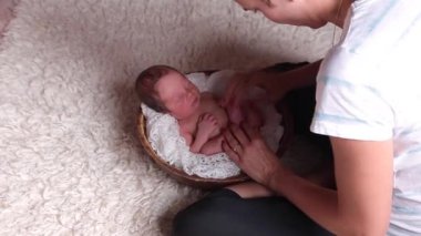 Kadın / anne yeni doğmuş bebeği beyaz bezle dolu bir sepetin içine koyar ve yeni doğan fotoğraf çekimine hazırlanır.