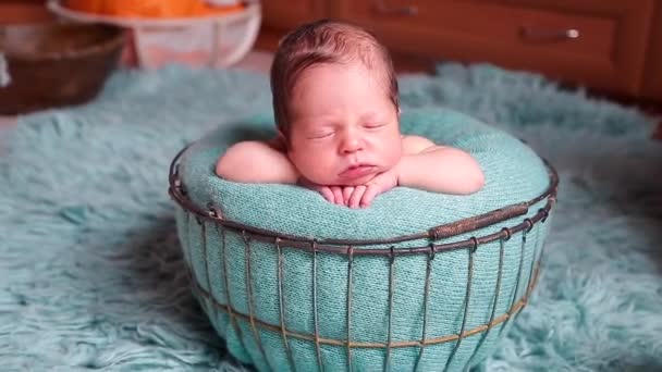 新生児は青い枕の上の邪悪な金属のバスケットで眠り 背景には青い昼寝のじゅうたんが 新生児の写真撮影の準備をしている — ストック動画