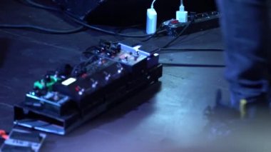 Siyah ayakkabı bir adamın ayağı ayarlar ve gitar işlemci kolları anahtarları, bir gece kulübünde çekim, pedallar birkaç kez basar