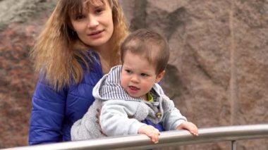 Küçük bir çocuk / çocuk metal çit, çocuk demir çubuk tutan, şımarık, anne bir şey söylüyor ve ona açıklar, hayvanat bahçesinde hayvanları izlerken bir anne