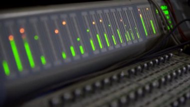 Kayıt stüdyosunda büyük karıştırma konsolu, çeşitli ses parçalarının ekolayzır ölçeğine yakın çekim, görünür ekran zaman kodu, yakın çekim