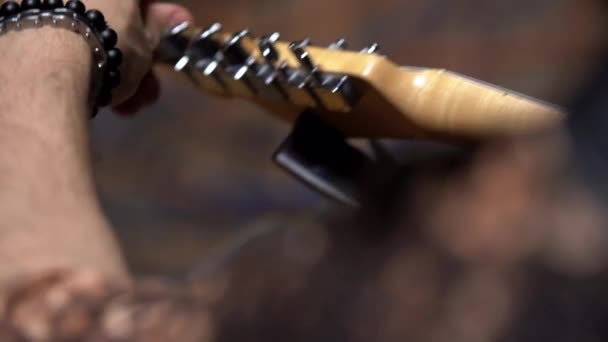 音乐家穿上吉他颈部音乐调谐器 扭动钉钉 并在表演前调整吉他 从背后拍摄 — 图库视频影像