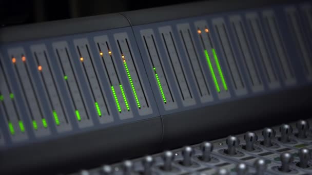 Égaliseur à la console d'enregistrement, à l'échelle des bandes lumineuses de vert et d'orange, gros plan. console de mixage, enregistrement sonore multicanal 