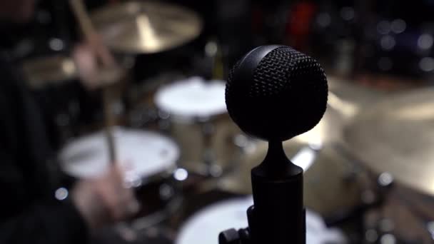 レコーディングスタジオ スタンドクローズアップ上の黒いマイク ドラムセットを演奏するバックグラウンドドラマーで 屋内撮影 人工照明 — ストック動画