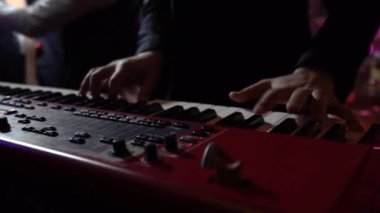 Kırmızı synthesizer üzerinde oynayan siyah gömlekli bir adam, bir gece kulübünde çekim, yakın çekim, konser, parti