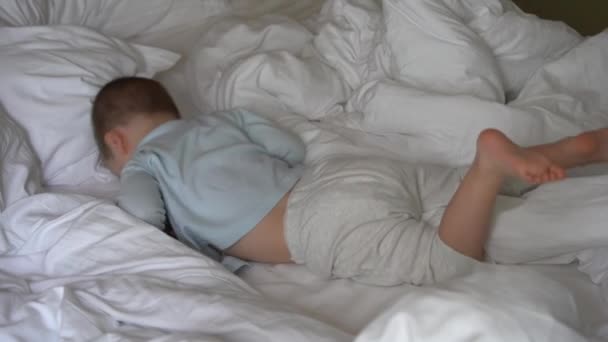 Ένα Μικρό Παιδί Νήπιο Είναι Ξαπλωμένο Στο Κρεβάτι Λευκά Σεντόνια — Αρχείο Βίντεο