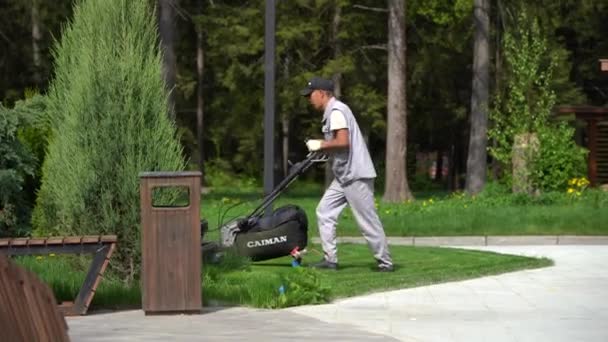 Ein Asiatisch Aussehender Mann Grauem Arbeitsanzug Und Schwarzer Mütze Mäht — Stockvideo