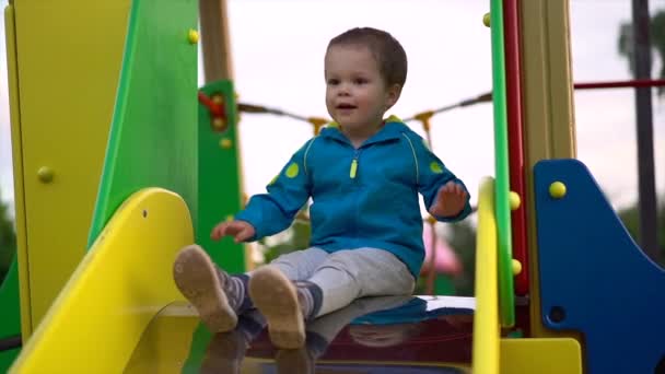 Baby Jongetje Blauwe Jas Grijze Broek Spelen Speelplaats Hij Glijdt — Stockvideo