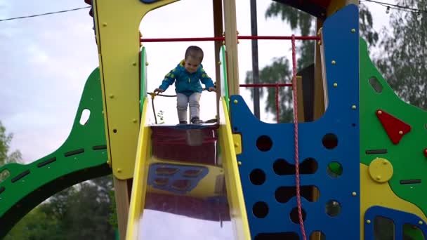 Dítě Chlapeček Modrém Kabátku Šedých Kalhotách Hrají Hřišti Pohybuje Kovové — Stock video