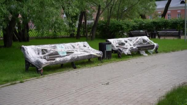 公园里的两张长椅 用胶卷包裹着 红白相间的带子 限制着考罗纳维的活动 社交距离 在一个多风的夏日拍摄 — 图库视频影像
