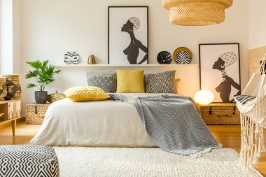Yatakta modern sıcak yatak odası iç posterler ve bitki ile sarı ve desenli yastıklar