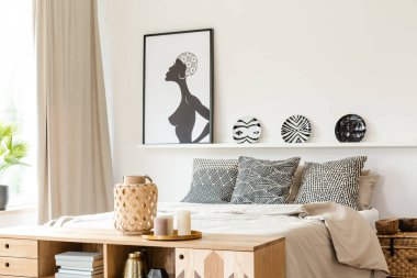 Siyah ve beyaz yastıklar, desenli plakalar ve Afrika posterdeki bir etnik yatak odası iç