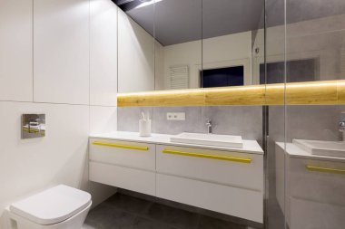 Temiz, modern banyo iç bir tuvalet, beyaz dolapları, sarı kulplar, aynalar ve gri karo ile