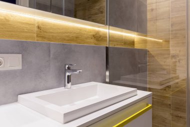 Lavabo musluk zarif banyo iç gri ve ahşap duvara ile yakın çekim