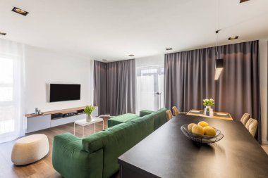 Modern geniş düz iç yemek masası üzerinde çiçekli beyaz kabarık yakınındaki yeşil kanepe 