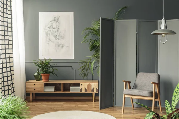 リビング ルームのインテリアに木製の食器棚の上の成形 暗い壁に掛かっている図面の横にある灰色の画面に対してレトロ肘掛け椅子 — ストック写真