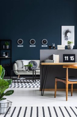 Duvardaki bir masa ve sandalye ve bir kanepe ve saatler oturma odası ile bir ev ofis iç önden görünümü